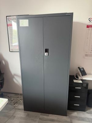 a metal cabinet in the corner of a room next to a desk