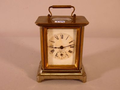 une petite horloge en laiton avec des chiffres romains sur le cadran