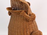 a wicker bag with a cat sitting inside of it