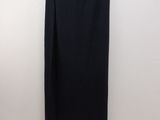 a black skirt hanging on a hanger against a white wall
