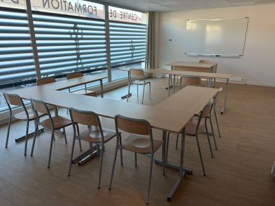 tables and chairs in a room with a large window and a whiteboard