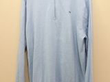 a light blue sweater hanging on a hanger against a wall