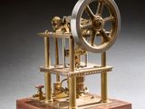 une vieille maquette de machine à vapeur posée sur un socle en bois