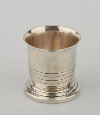 a silver cup on a stand on a white surface