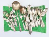 a lot of silver spoons and forks on a green cloth