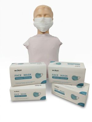 trois boîtes de masques faciaux et une tête de mannequin sur fond blanc