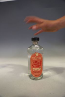 a bottle of alcohol sitting on a counter with a hand reaching for it