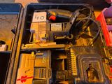 une boîte à outils contenant un marteau, une perceuse et d'autres outils, posée sur une table