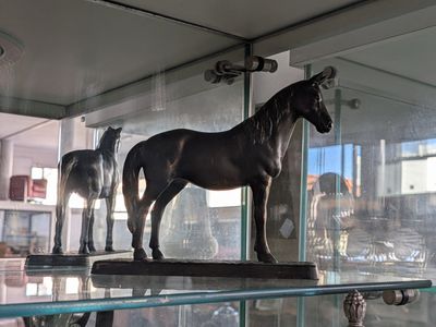 three statues of horses on display in a glass case