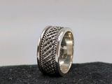 gros plan d'une bague en argent sur une surface noire