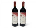 two bottles of red wine sitting next to each other on a white surface
