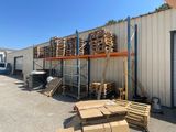 Plusieurs palettes de bois sont empilées devant un bâtiment