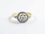 un gros plan d'une bague en diamant et en or posée sur une surface blanche