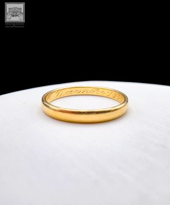 a close up of a gold wedding ring on a white surface