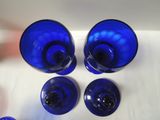 four blue glass vases sitting on a white table