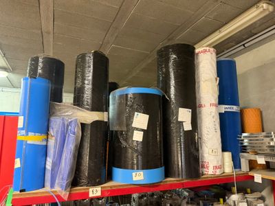 de nombreux rouleaux de plastique noir sur une étagère dans un entrepôt