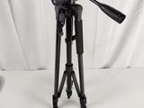 a black tripod sitting on top of a white table next to a camera