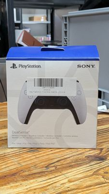 La boîte de la manette PlayStation est posée sur une table en bois.