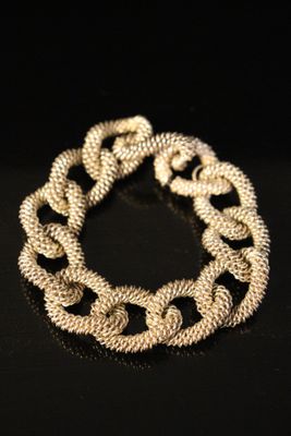 a close up of a gold chain bracelet on a black surface