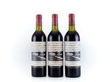 trois bouteilles de vin rouge posées l'une à côté de l'autre sur une surface blanche