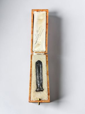 a small black object in a wooden box on a white surface