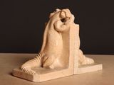 une statue représentant une femme tenant un livre posé sur une table
