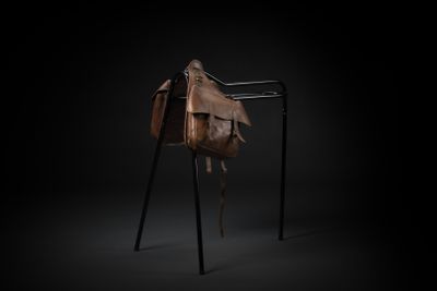a brown leather bag sitting on top of a metal stand