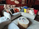 un salon avec un canapé, un fauteuil, un pouf et une table basse