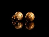 une paire de boucles d'oreilles en or sur un fond noir, avec des reflets