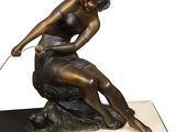 bronze statue of a woman sitting on a rock with a dog