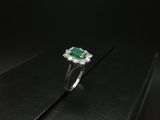 une bague en émeraude et diamant sur une surface noire