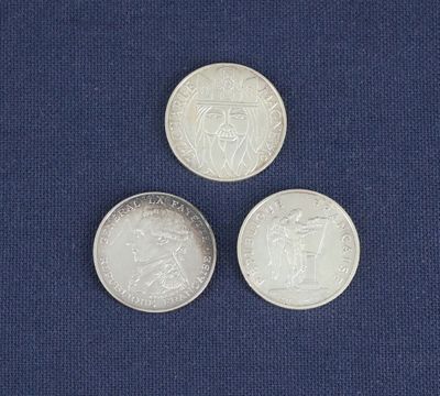 trois pièces de monnaie britanniques différentes posées sur un tissu bleu avec un fond blanc