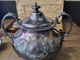 a silver tea pot sitting on a table next to a silver plate