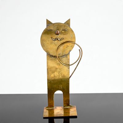 sculpture représentant un chat tenant une bague dans la gueule, posée sur un fond noir