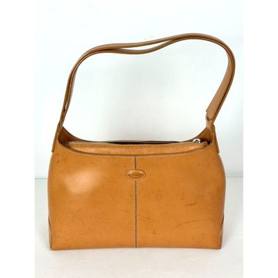 une image représentant un sac à main marron muni d'une anse, posé sur une surface blanche