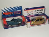two boxes of toy cars sitting on top of a white surface
