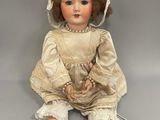 an antique doll sitting on the floor with a hat on