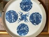 une assiette bleue et blanche posée sur une étagère à côté d'un tableau