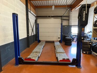 a picture of a garage with a car lift in the middle of the room