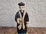 une figurine en céramique représentant un homme portant un chapeau et un manteau