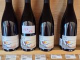 four bottles of wine are on a wooden shelf in a wine shop