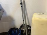 a washing machine and a vacuum in the corner of a bathroom