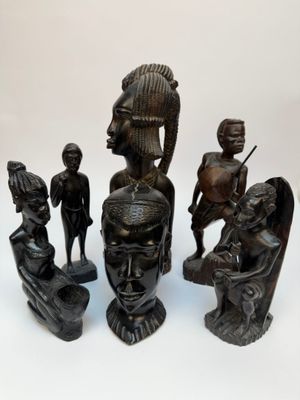 plusieurs figurines africaines empilées les unes sur les autres sur une surface blanche