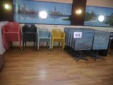 de nombreuses chaises et tables dans une pièce où est accroché un tableau au mur