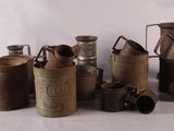 a lot of old milk cans sitting on a table