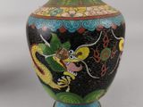 a black vase with a dragon on it on a table