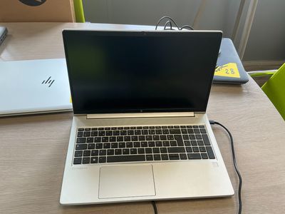 an open laptop computer sitting on top of a wooden table next to a green chair