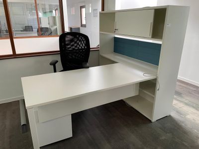 a white desk with a black chair next to a window