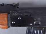 an old machine gun with a wooden handle on a gray surface
