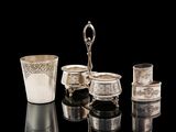 a silver cup and other silver objects on a black surface